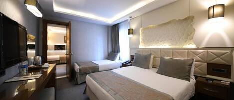 A hotel room with two beds, a desk with a chair, a TV, and a large decorative wall piece.