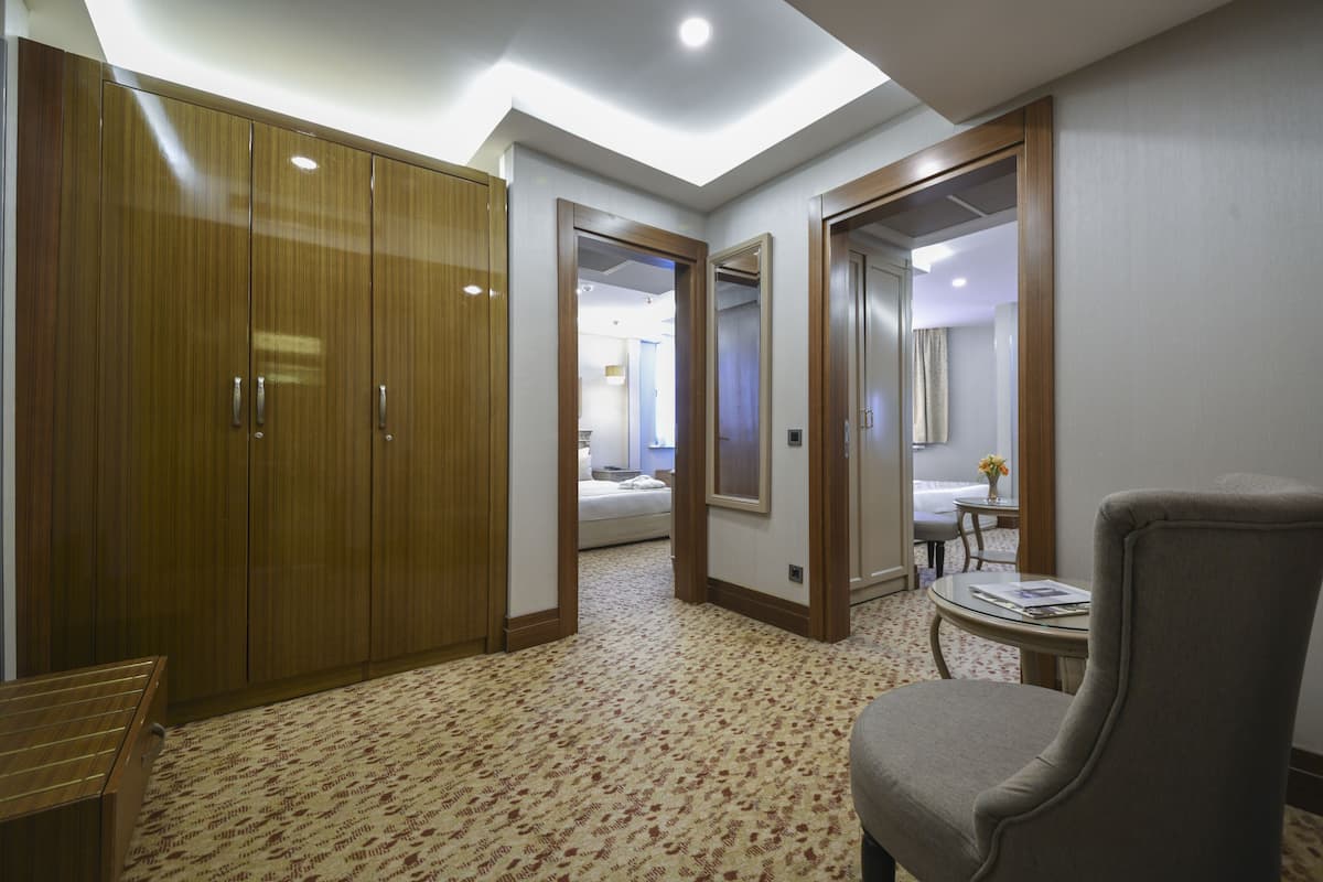 A hotel room with a large wardrobe, a small round table with a chair, and a mirror on the wall.