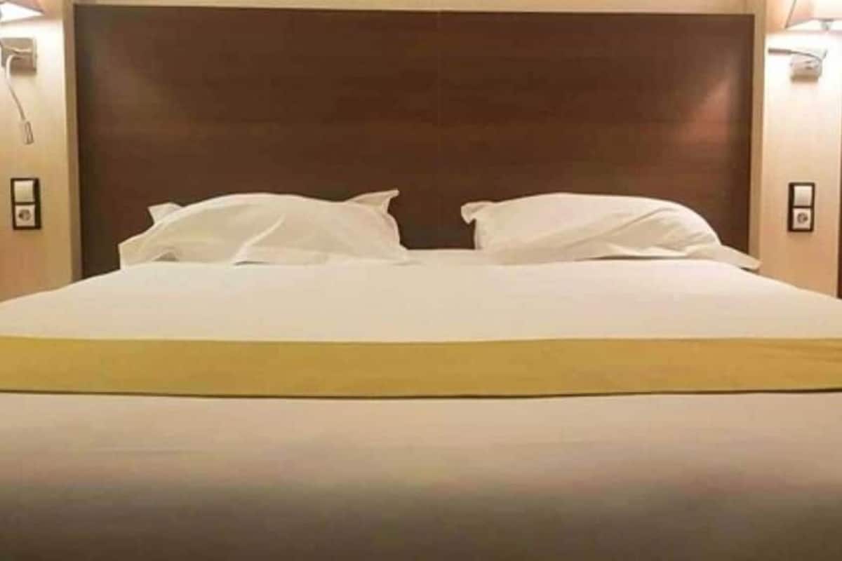 Quarto de hotel com uma cama grande, duas luminárias de cabeceira e uma cabeceira.