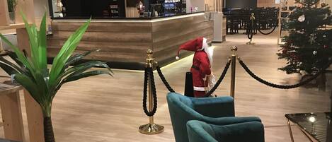 Un vestíbulo con zonas de estar, un mostrador de recepción, un árbol de Navidad y una zona de bar.