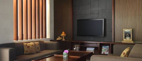 Una sala de estar moderna con un sofá, una mesa de centro y un televisor de pantalla plana montado en una pared de piedra.