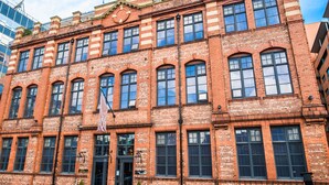 A red brick building with multiple windows and a flag. - Great John Street Hotel (Manchester)
