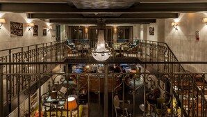 A multi-level hotel lobby with a grand chandelier, ornate railings, and a variety of seating areas. - Great John Street Hotel (Manchester)