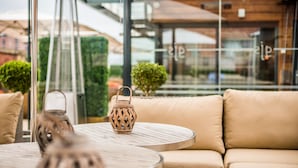 A round wooden table with a woven lantern and a beige sofa with cushions. - Great John Street Hotel (Manchester)
