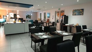 Un ristorante moderno con un'area bar centrale, diversi tavoli e sedie. Sono disponibili varie disposizioni di posti a sedere, tra cui cabine e tavoli singoli. L'ambiente presenta colori neutri, opere d'arte alle pareti e una disposizione pulita e ordinata.