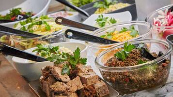 A buffet with various dishes including meatloaf, lentil salad, and pasta.