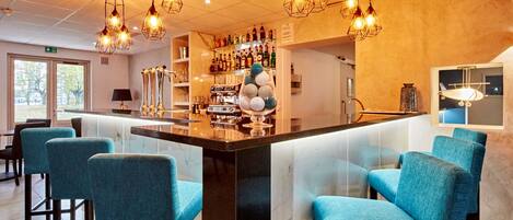 Una zona de bar con mostrador de mármol, taburetes tapizados en azul y lámparas colgantes.