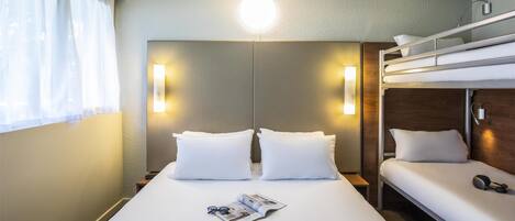 A hotel room with a large bed, two bedside tables, a bunk bed, and a window with curtains.