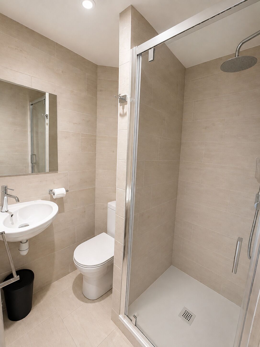 A modern bathroom with a glass-enclosed shower, a white sink, and a toilet.