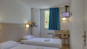 A hotel room with two beds, a TV mounted on the wall, a window with curtains, and a small bathroom area. - Cyan Hotel Roissy Villepinte Parc Des Expositions (Villepinte)