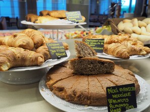 A bakery display with various baked goods including croissants, a cake with walnuts, almonds, and hazelnuts, and other pastries.