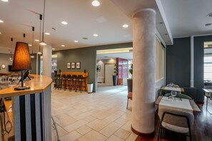 A spacious hotel lobby with a reception desk, seating area, and a view of the adjacent restaurant. - Tulip Inn Turin West (Rivoli)