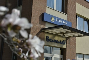 Um hotel com uma placa que diz 'Tulip Inn' e 'Benvenuti', indicando uma entrada acolhedora.
