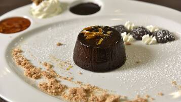 A dessert plate with a chocolate lava cake, powdered sugar, and chocolate-covered strawberries.