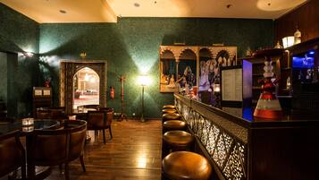 A bar area with wooden flooring, leather bar stools, and a decorative wall with a framed picture.