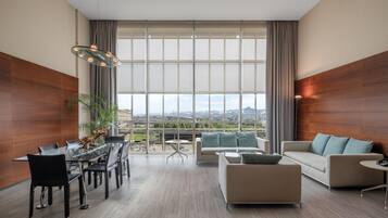 A modern living room with a dining area, large windows, and a view of the cityscape.