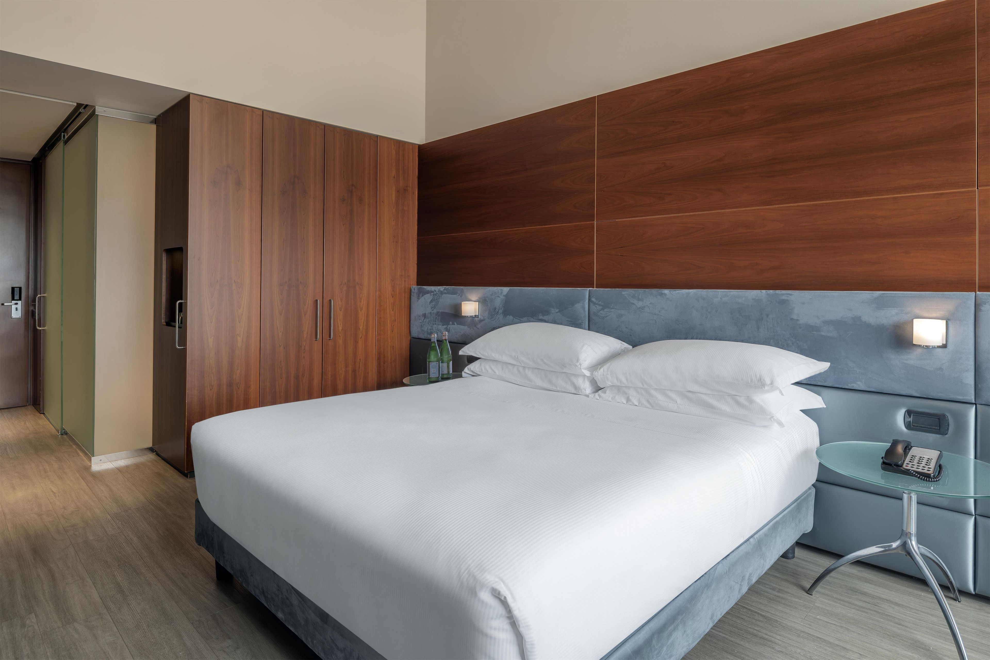 A hotel room with a bed, bedside table, and a wardrobe.