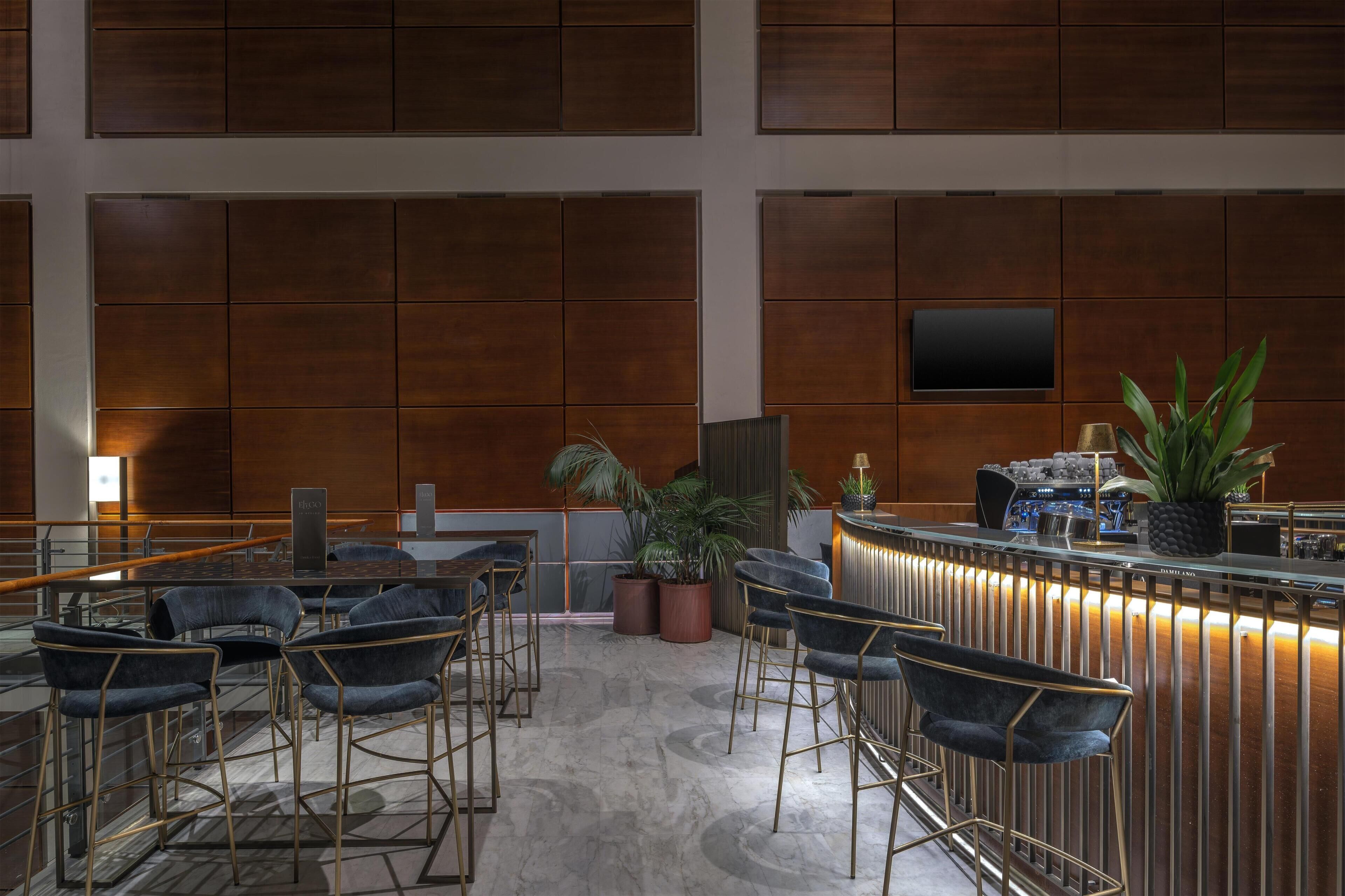 Un'area bar moderna con un bancone, sgabelli e piante in vaso.