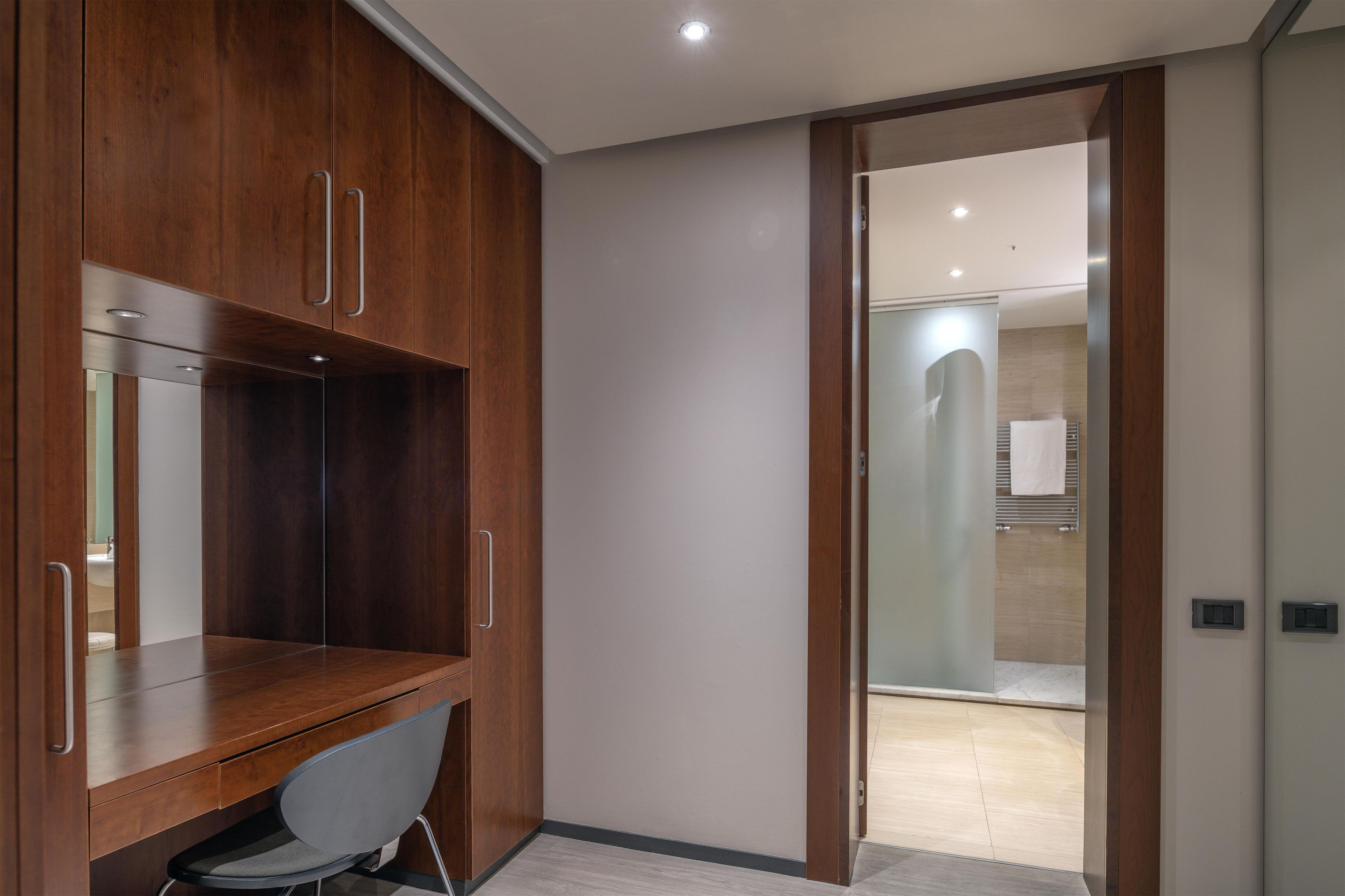 Un baño moderno con ducha, toallero y un inodoro visible a través de una puerta de cristal.