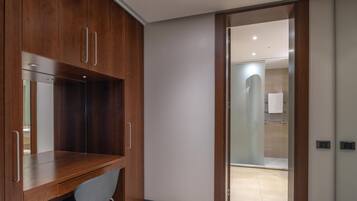 Un baño moderno con ducha, toallero y un inodoro visible a través de una puerta de cristal.