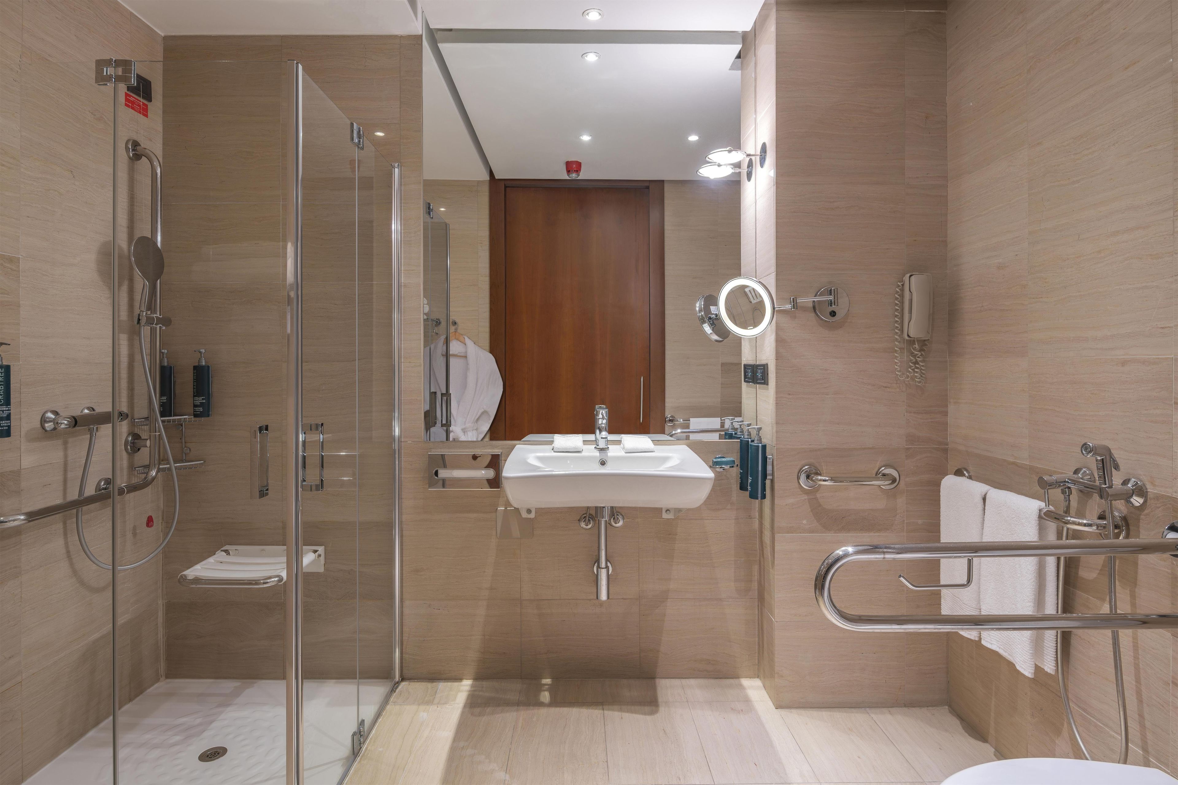 Un baño moderno con ducha de vidrio, lavamanos con espejo e inodoro.
