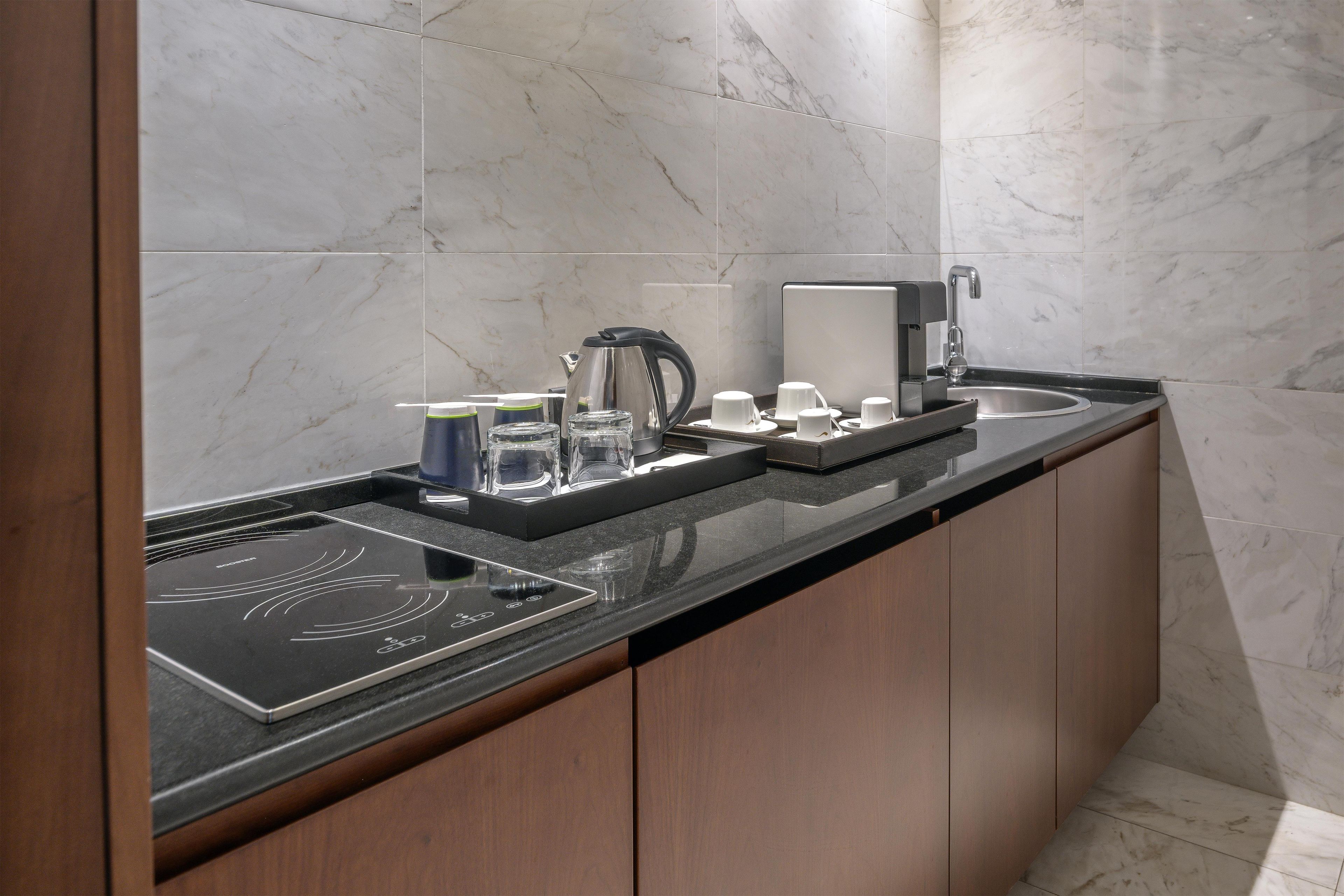 Cocina moderna con encimera negra, placa de inducción integrada, cafetera y lavabo.