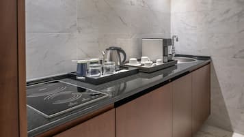 Cocina moderna con encimera negra, placa de inducción integrada, cafetera y lavabo.