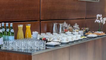 A buffet setup with various food items, beverages, and glassware.