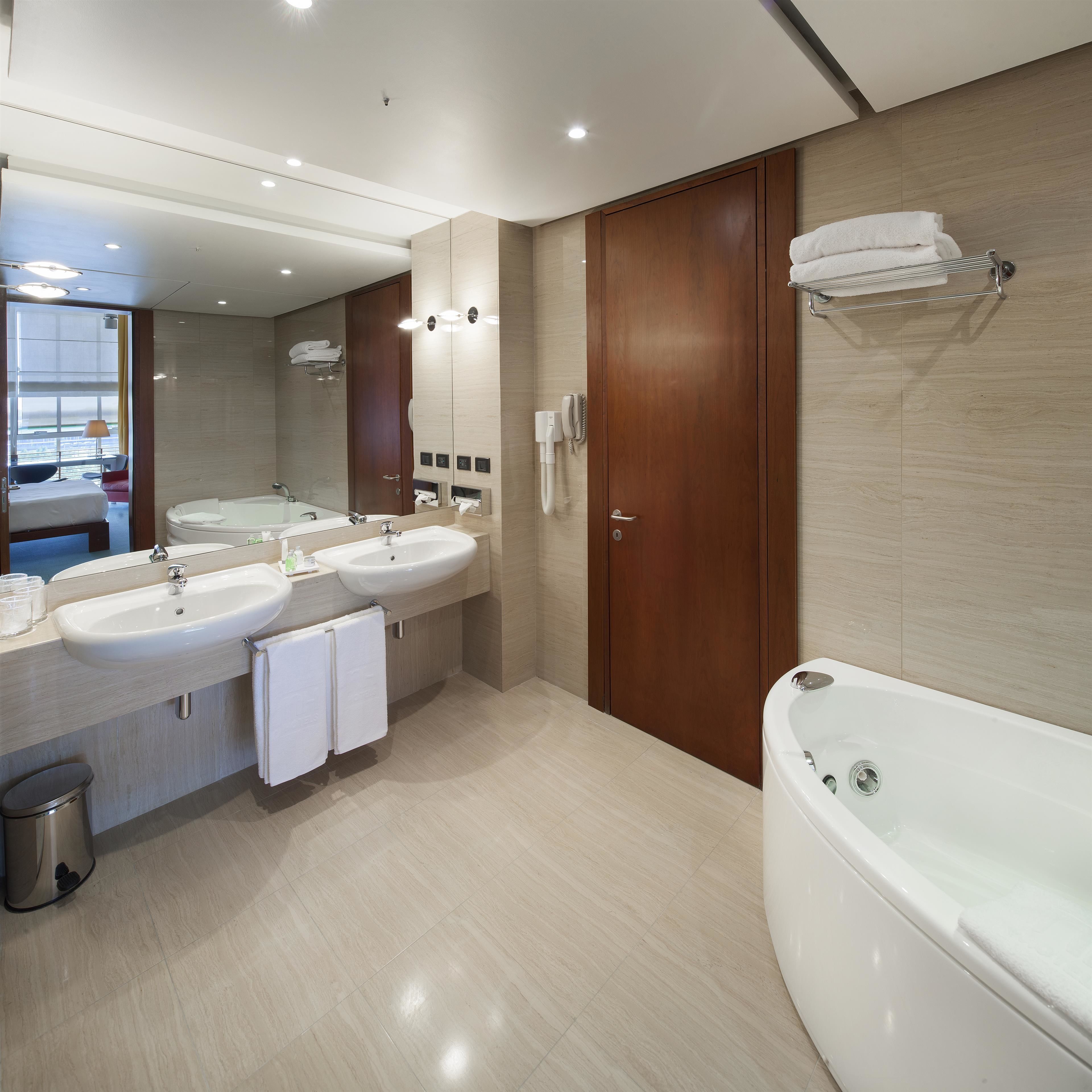 A modern bathroom with two sinks, a large bathtub, and a mirror.