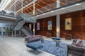A spacious lobby with a high ceiling, a staircase, and a seating area with sofas and a coffee table.