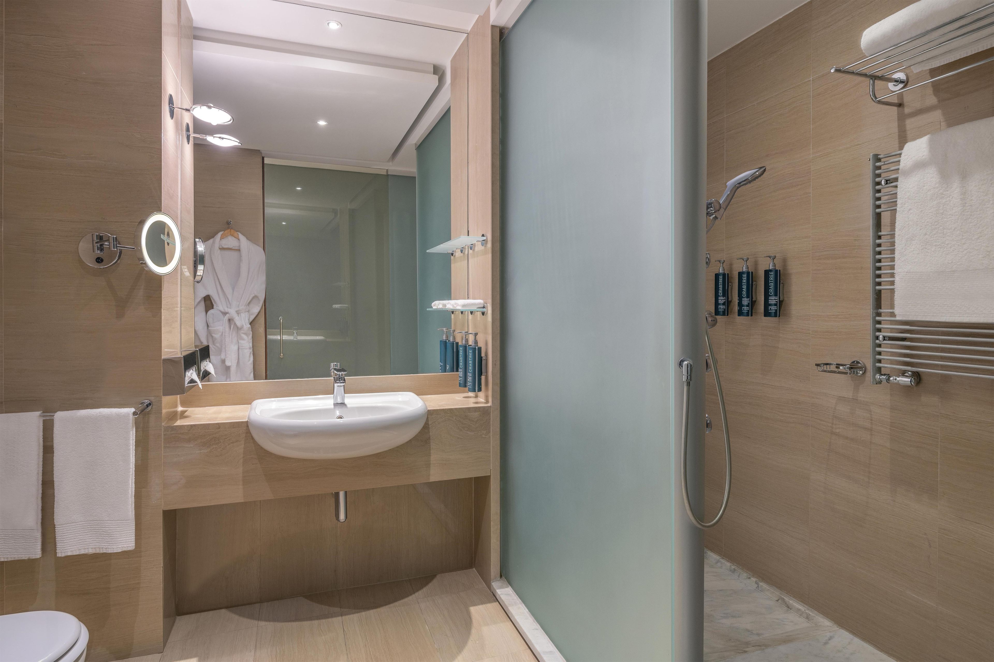 A modern bathroom with a sink, mirror, towel rack, and shower.