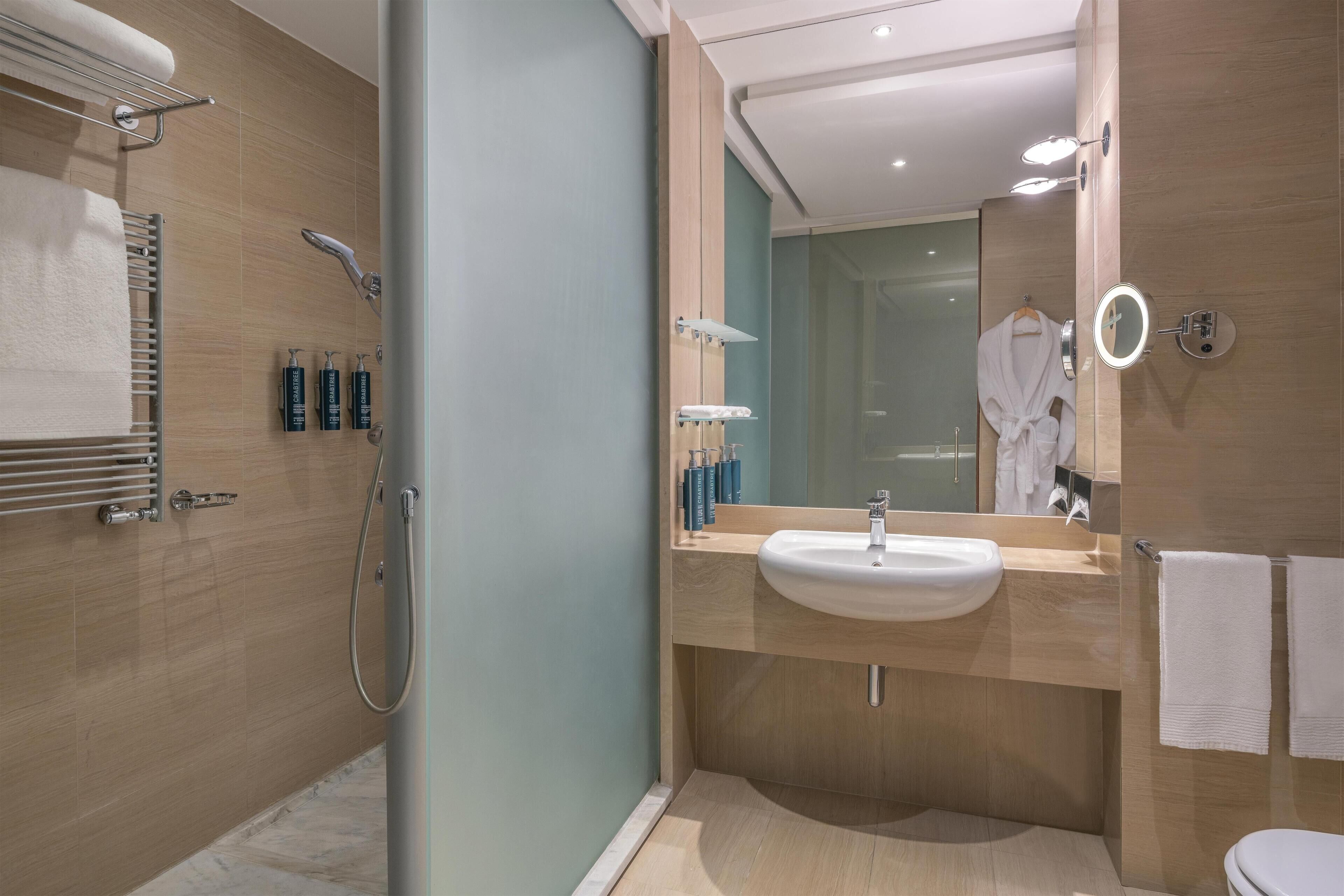 Une salle de bain moderne avec une douche à l’italienne, un lavabo et un miroir.