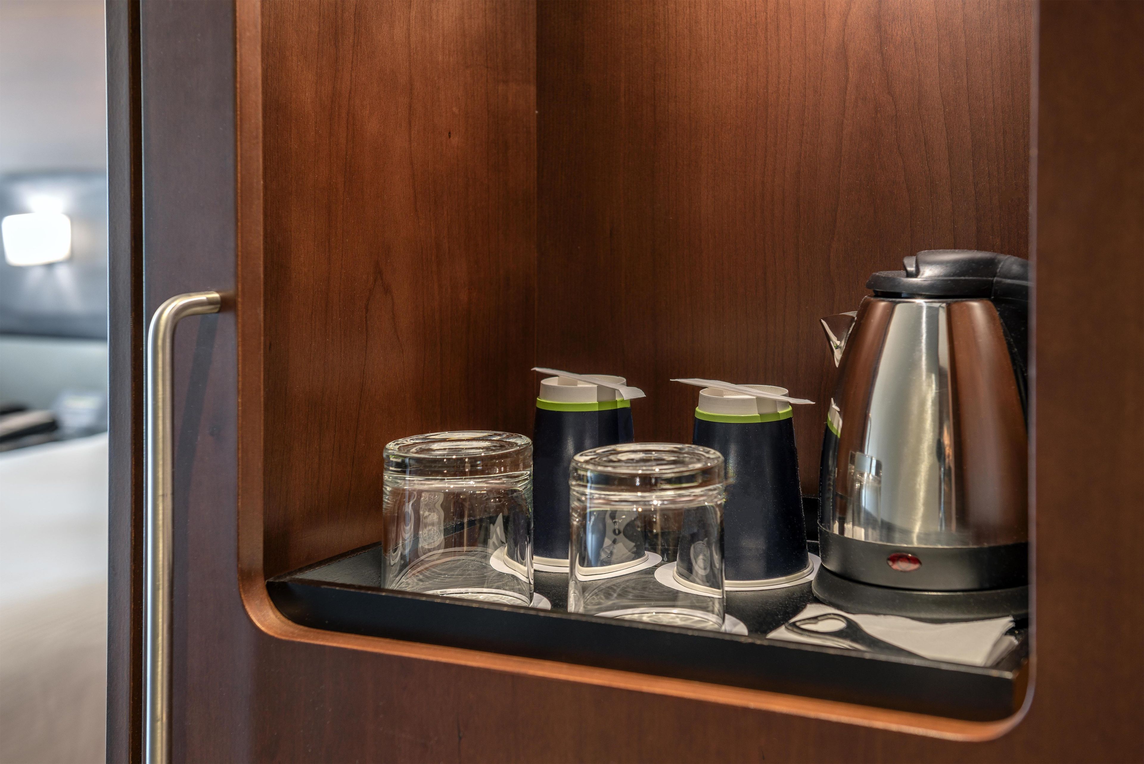 Un interior de madera con una estantería empotrada que contiene una cafetera, dos vasos de vidrio y una taza.