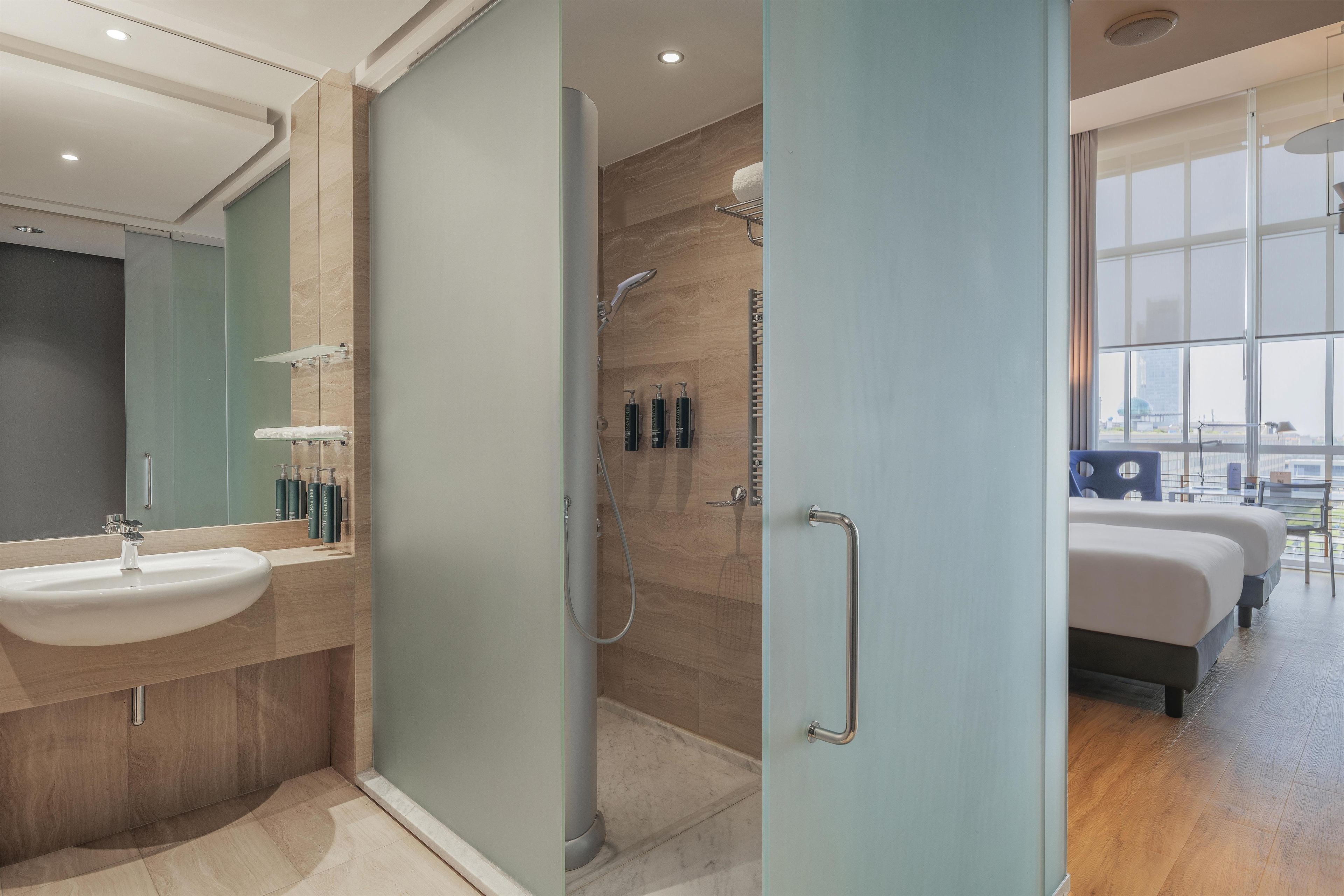 A modern bathroom with a glass shower enclosure, a sink, and toiletries.