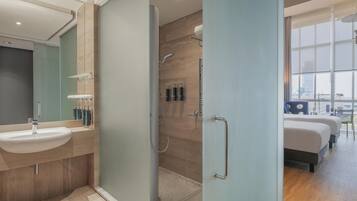 A modern bathroom with a glass shower enclosure, a sink, and toiletries.