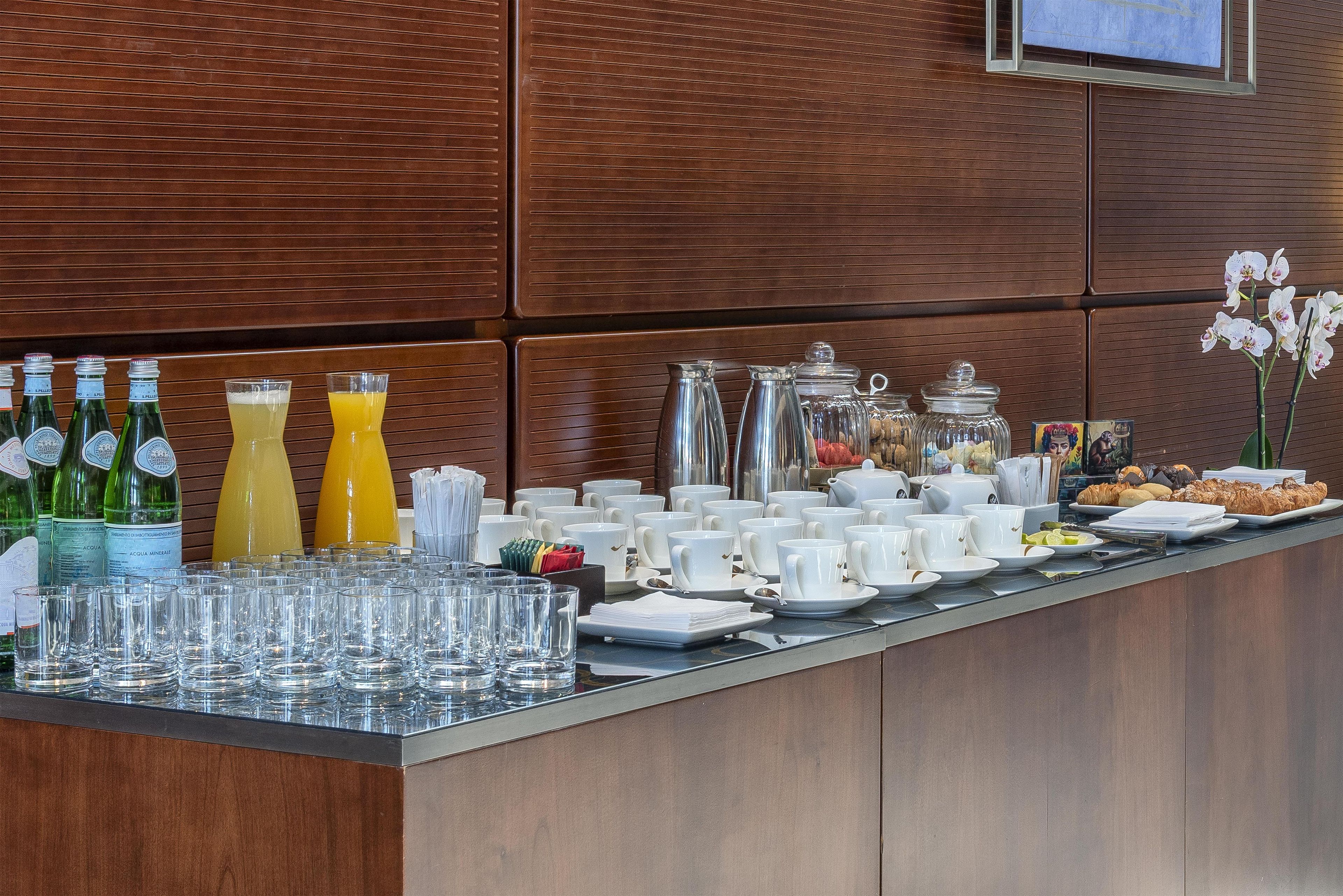 Una mesa de buffet con diferentes alimentos, bebidas y vasos.