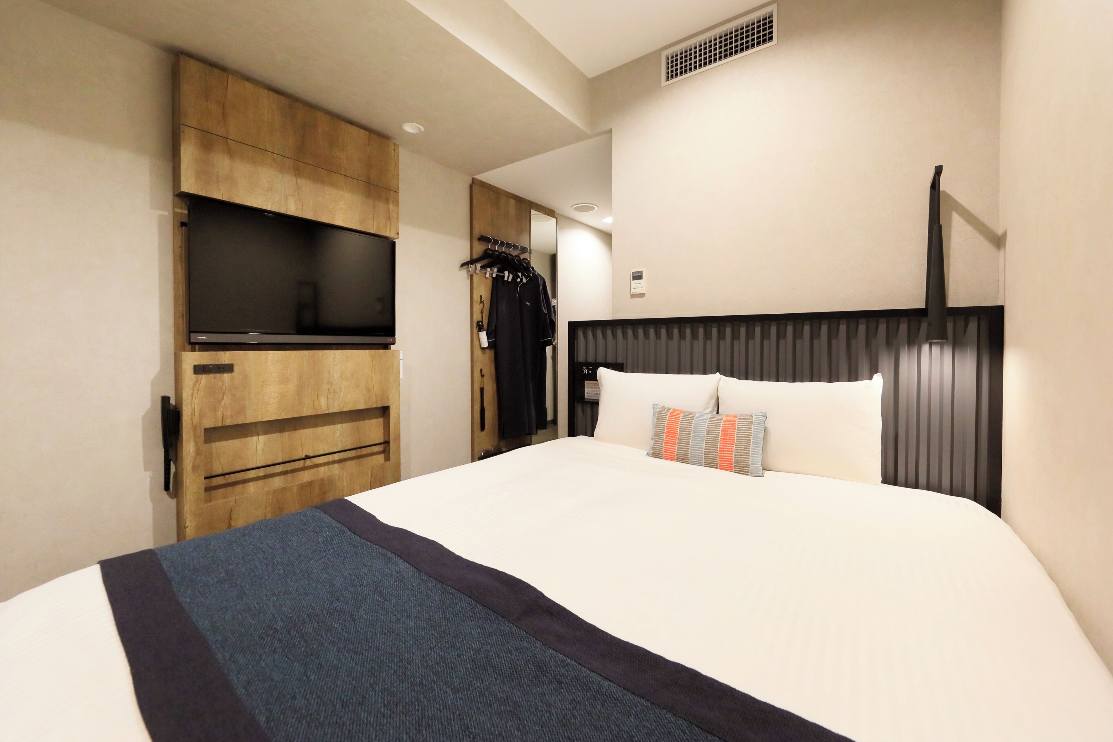 Une chambre d’hôtel équipée d’un lit, d’une télévision, d’une armoire et d’un porte-manteau.