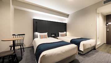 A hotel room with two beds, a desk, and a chair.