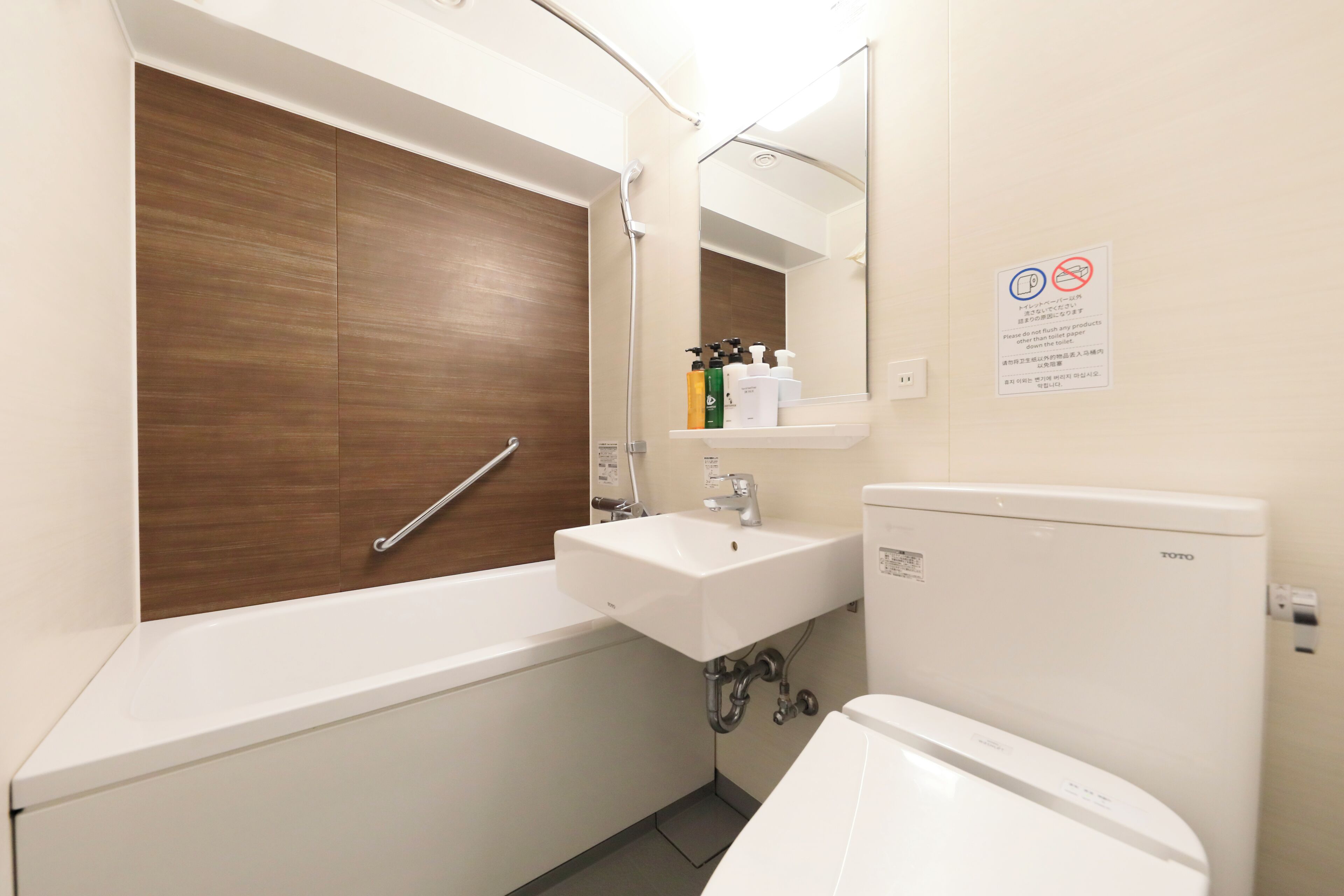 A modern bathroom with a wooden vanity, a white sink, and a TOTO toilet.