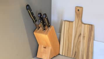 A wooden knife block with knives and a wooden cutting board on a countertop.