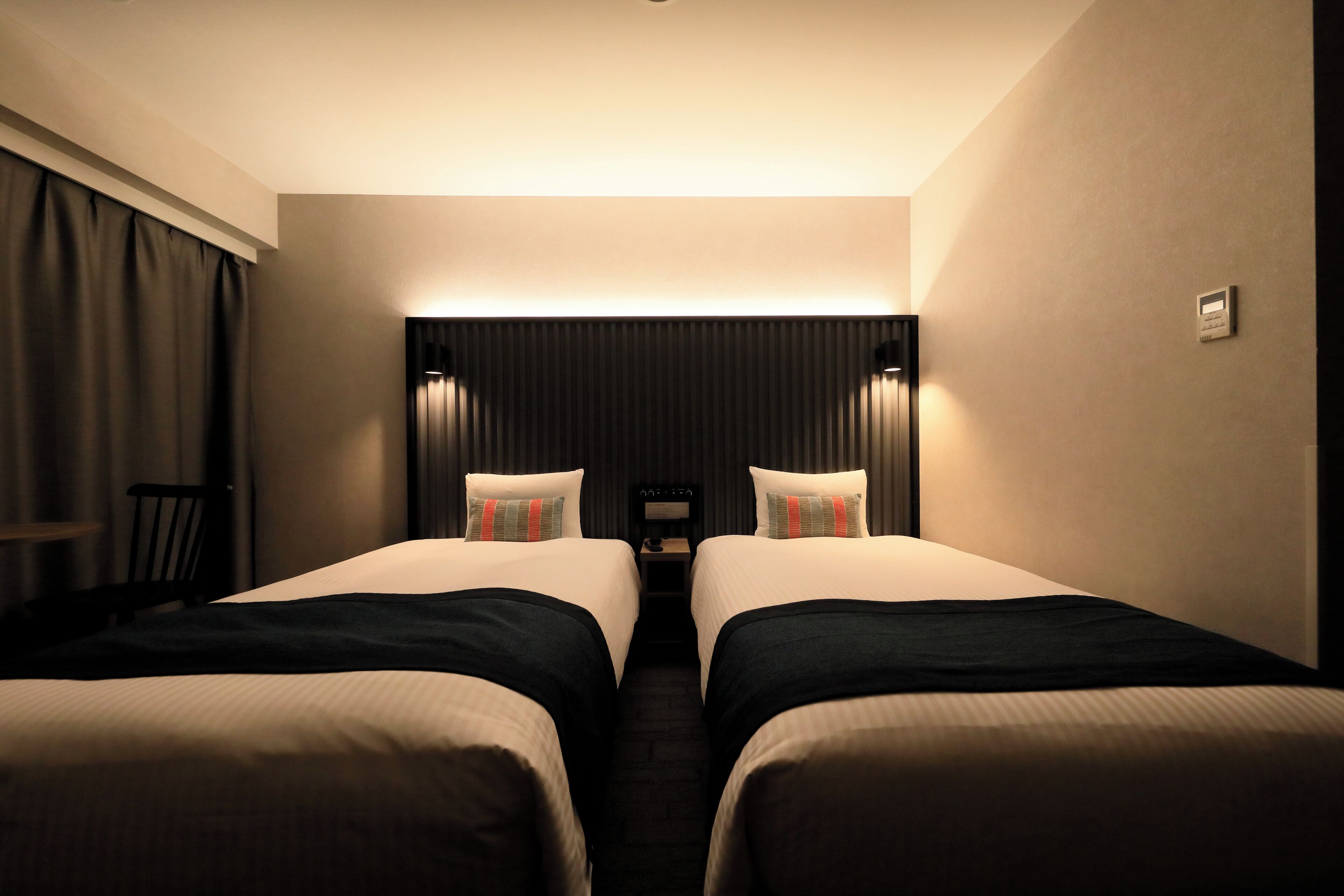 A hotel room with two beds, a desk, and a chair.