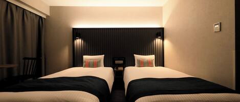 A hotel room with two beds, a desk, and a chair.