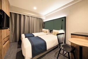 A hotel room with two beds, a desk, a chair, a television, and a large window with curtains.