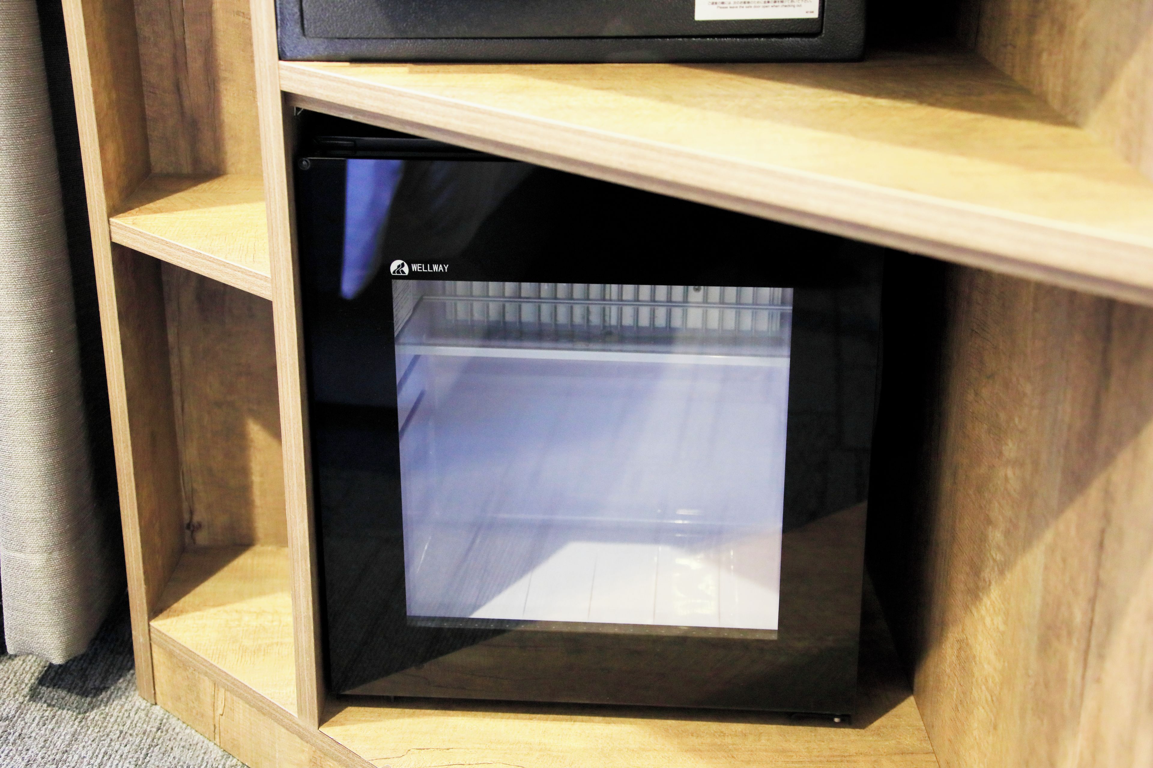A black refrigerator with a label 'WELLWAY' in a wooden cabinet.