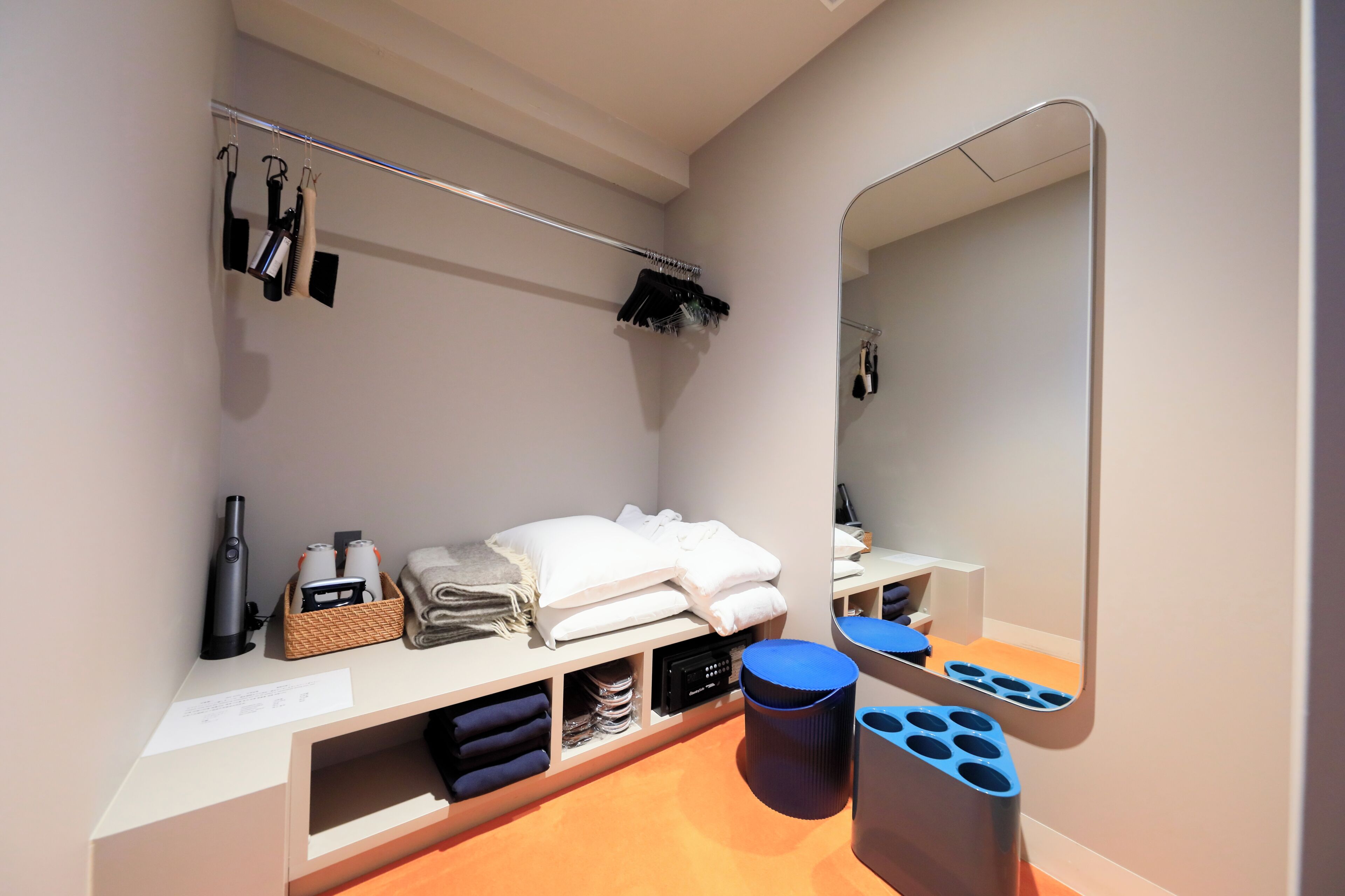Een hotelbadkamer met een spiegel, handdoekrek en opbergplanken.
