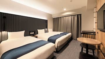 A hotel room with two beds, a desk, a chair, and a TV mounted on the wall.