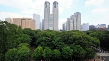 A cityscape with modern high-rise buildings and dense green trees.