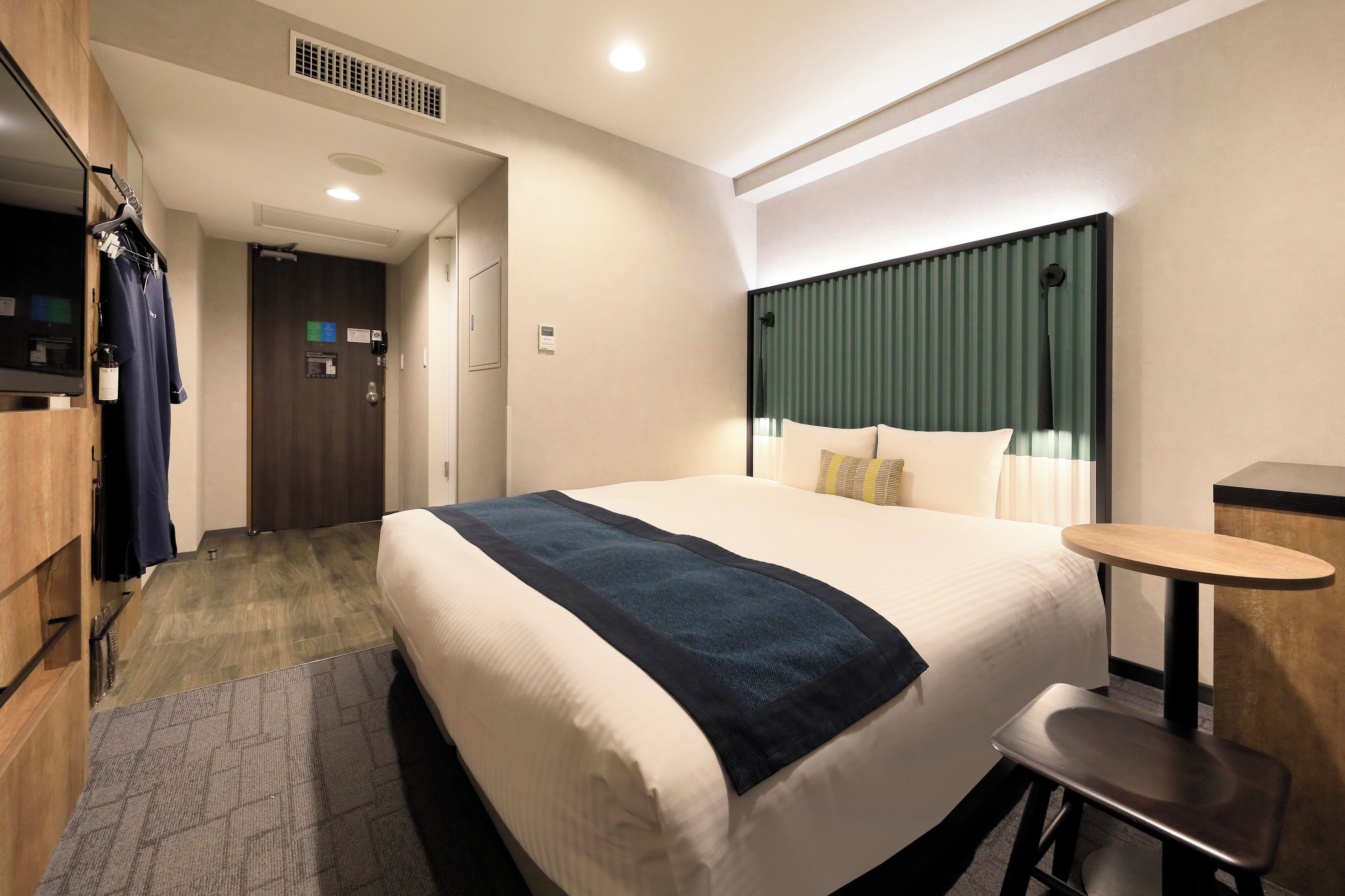Una habitación de hotel con una cama grande, un escritorio, una silla, un televisor y un armario.