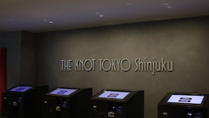 A reception area with a sign reading "THE KNOT TOKYO SHINJUKU" and several digital kiosks.