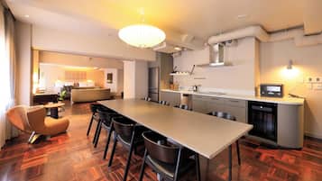 A modern kitchen with a long dining table, chairs, and a built-in oven.